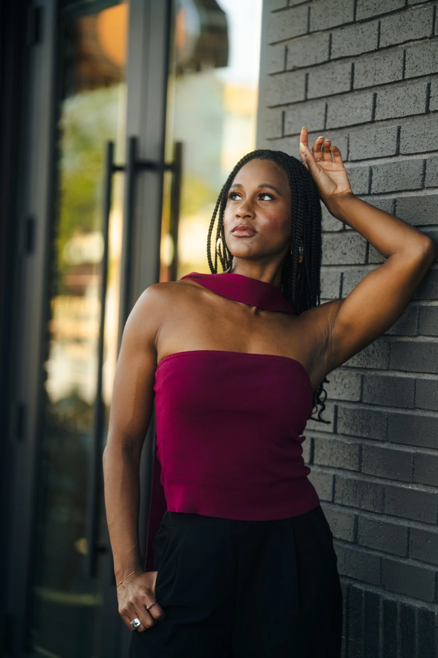 Jasmine Neely in a burgundy top beside a dark brick wall