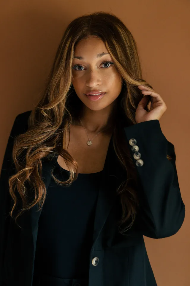 Sydney Leah seated in a black suit for an editorial portrait